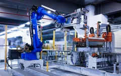 Industrieroboter in einer Fertigungshalle, kühles blaues Licht.